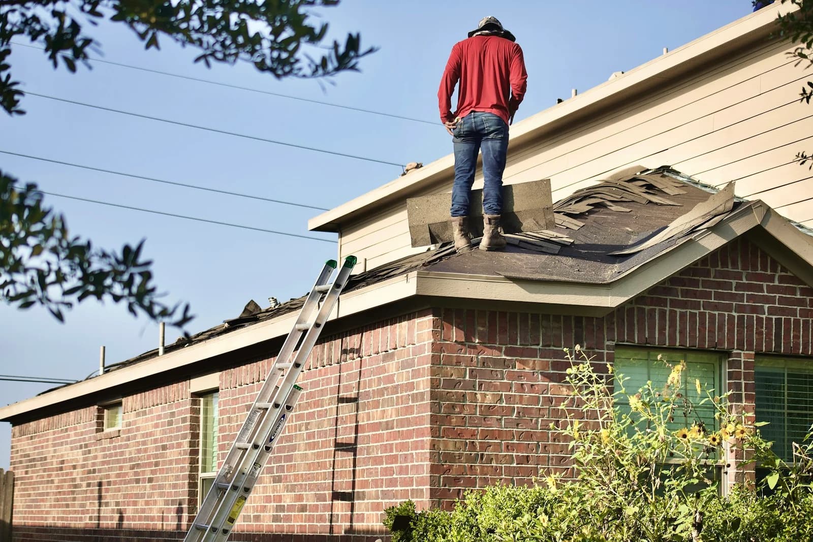 A roofer working on the roof of a brick house at Crest Roofing