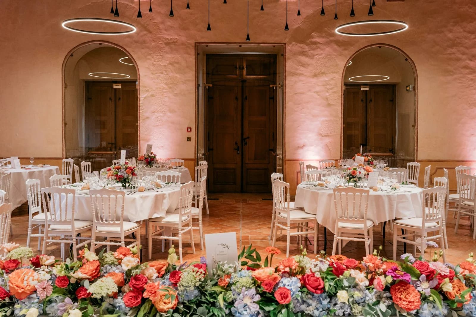 An elegant reception room with floral arrangements and round dining tables at The Meadow House